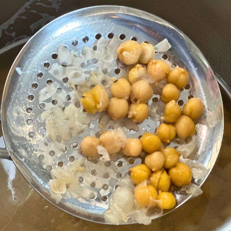 removing chickpea skins with a slotted spoon after noiling