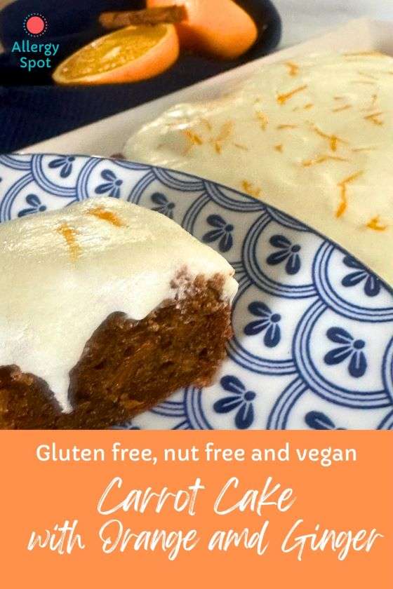Vegan nut and gluten free orange cake with frosting on blue and white plate with fresh oranges and cinnamon