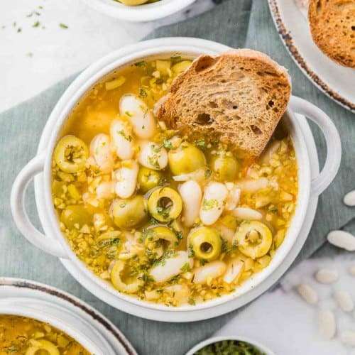 Greek green olive soup in white dish with bread
